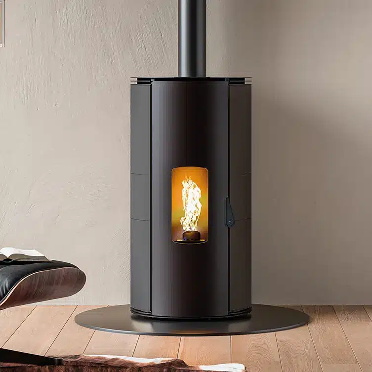 Poêle à Granulés Noir Design Moderne et Contemporain Poêle à granulés noir cylindrique au design moderne avec flamme visible dans un salon contemporain sur parquet.