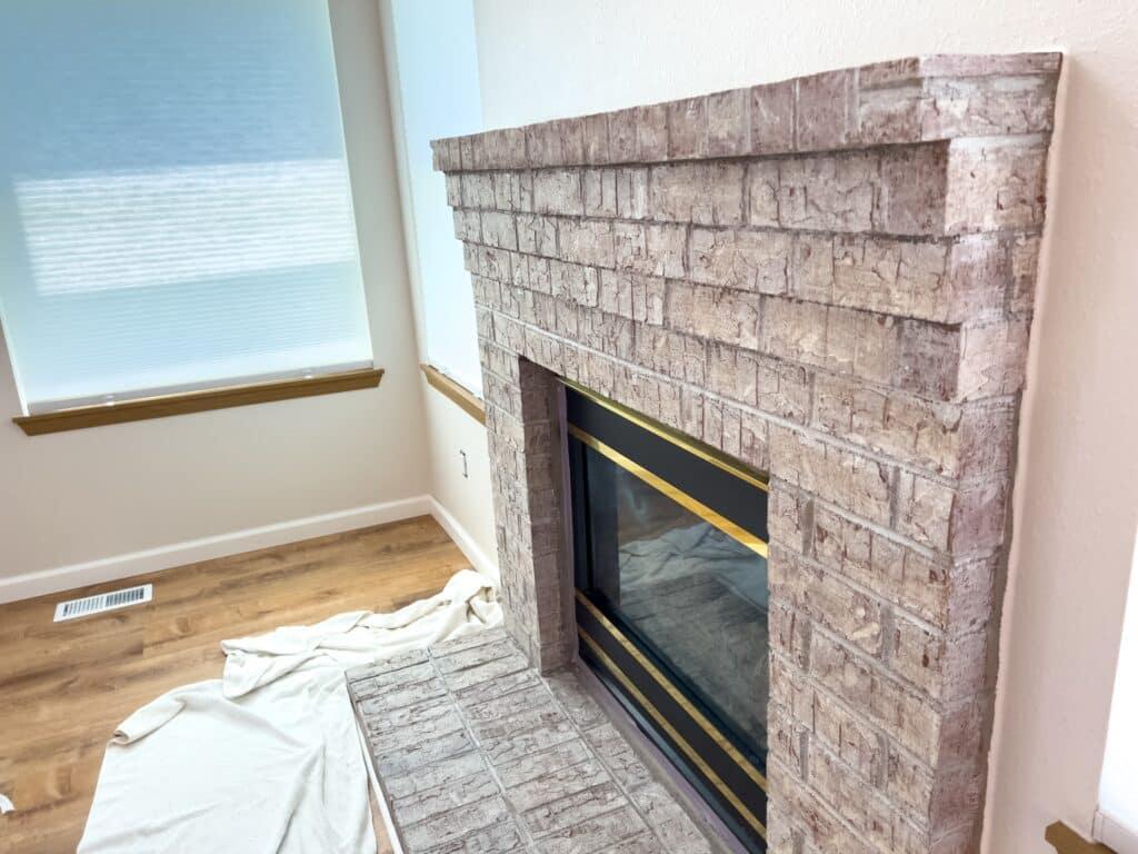 Cheminée en Briques Rustique avec Finition Dorée Élégante Cheminée rustique en briques beiges avec garniture dorée, située dans un salon lumineux avec parquet.