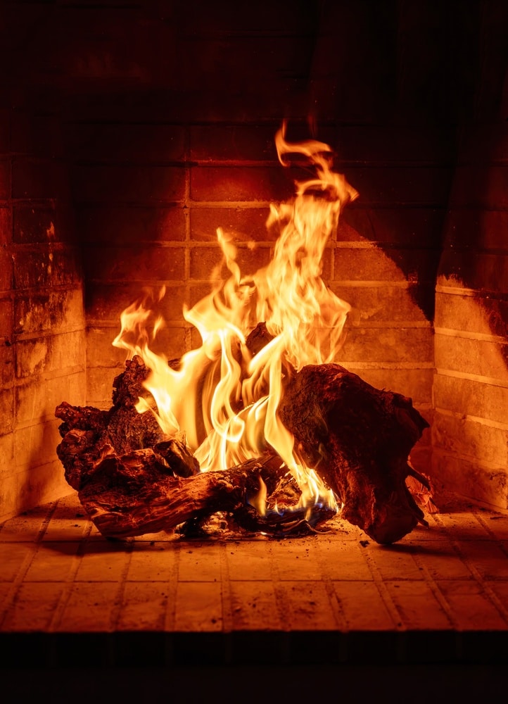 Feu de cheminée : ambiance chaleureuse et bois brûlant Flammes orangées sur des bûches de bois dans une cheminée en briques à l'ambiance chaleureuse et réconfortante.