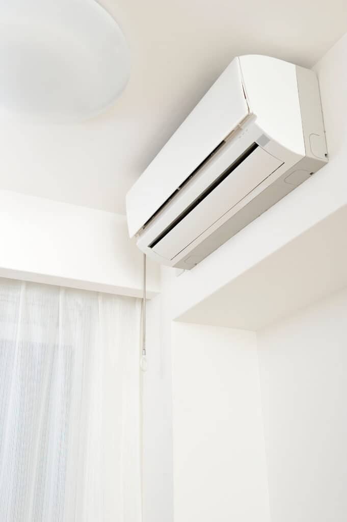 Climatiseur split blanc installé dans un salon moderne Unité de climatisation murale blanche installée dans une pièce lumineuse près d'une fenêtre et d'un plafonnier.