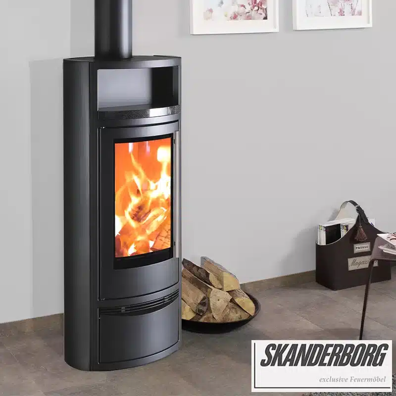 Poêle à Bois Moderne Skanderborg : Design Exclusif Feuermöbel Poêle à bois moderne Skanderborg noir allumé, design exclusif Feuermöbel, avec bûches de bois dans un salon épuré.