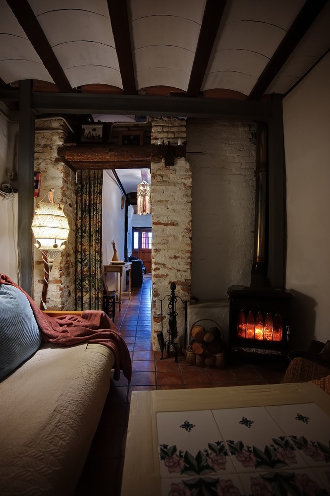 Salon Rustique Chaleureux avec Cheminée et Briques Salon rustique chaleureux avec cheminée allumée, murs en briques apparentes, poutres au plafond et canapé douillet.